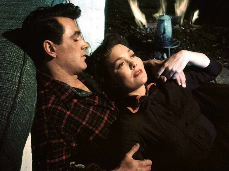 A man and woman lie down together next to a fireplace.