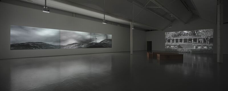 For IC-98's exhibition, the galleries are lit lowly. There are two projections on the walls - one shows a monochrome sea-scape, and the other shows a ruined building with Greek columns.