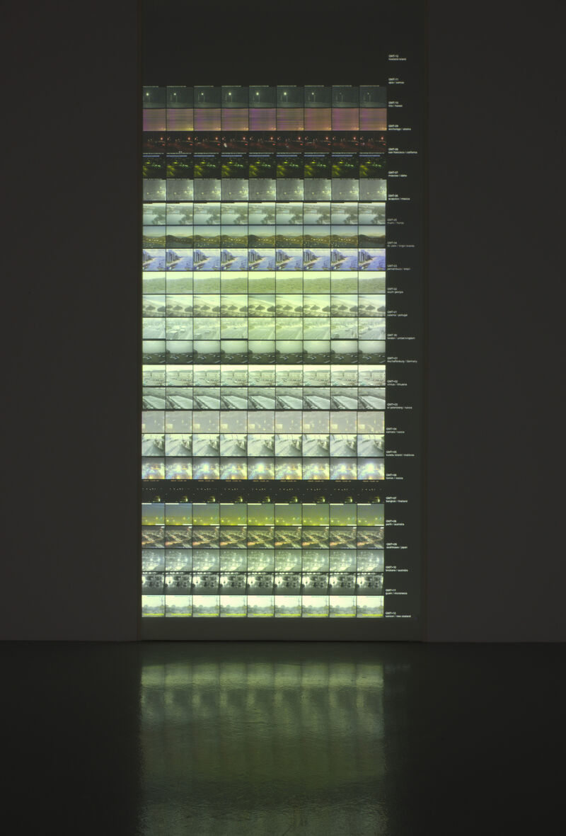 A green block is made out of lots of repeating, small images. The images are glowing and are projected on the wall.