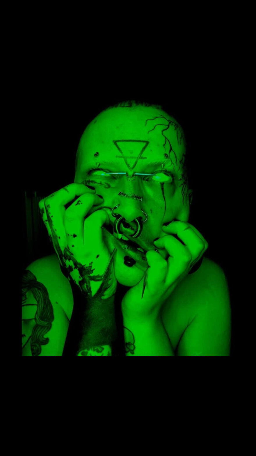 Person grabbing their face while lit by green light