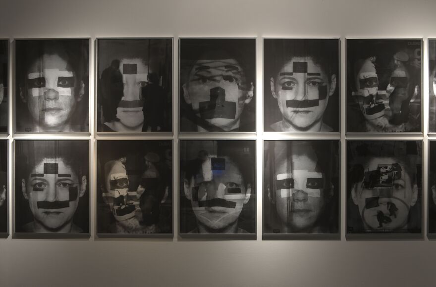 From Jane & Louise Wilson's exhibition. 10 black and white photographs of people's faces. Parts of their faces are blocked off by white and black spots and face paint.