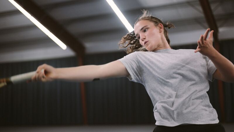 A teenage girl in mid-jump while playing tennis.