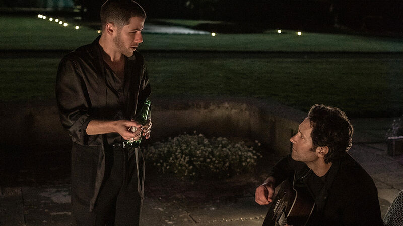 Two men play guitars outdoors at night.