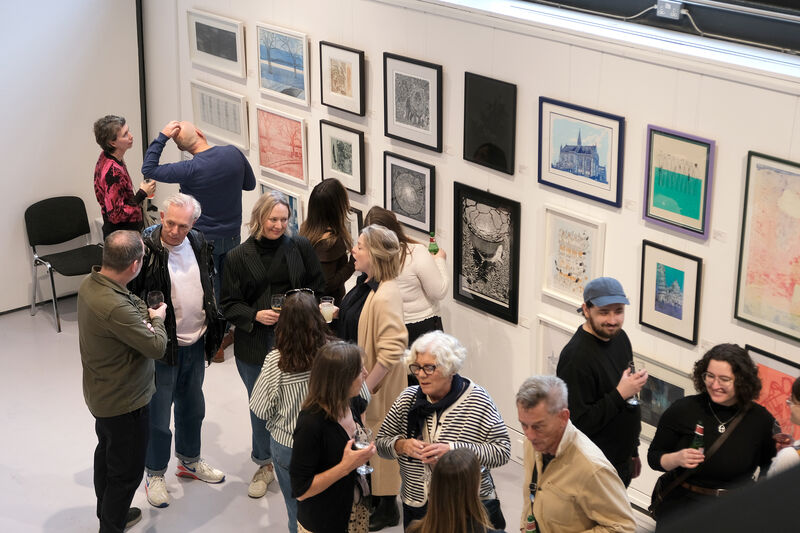 People talking in Centre Space surrounded by framed prints