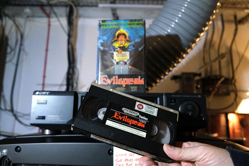 Person holding an Evilspeak VHS infront of a video player