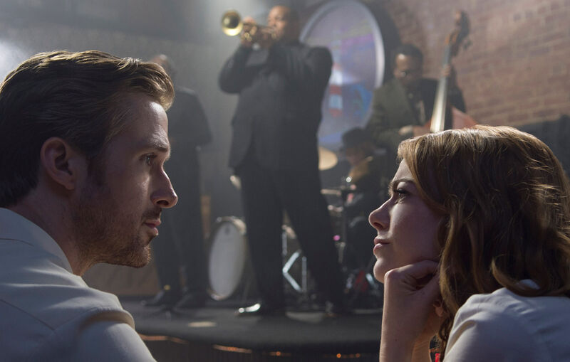 A man and woman stare into each others eyes in front of a stag where a jazz musician plays