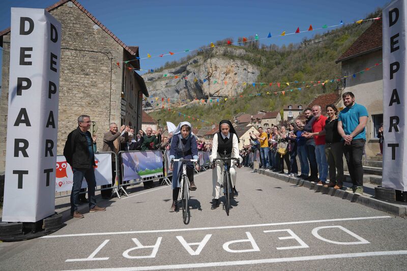 Two nuns ride bikes over the start line at a bike race.