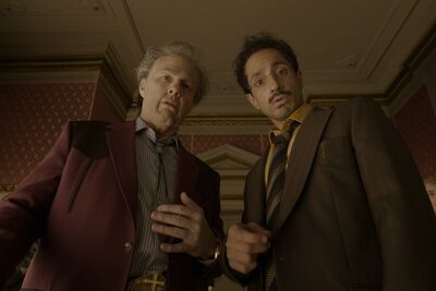 Two smartly dressed men look down towards the camera