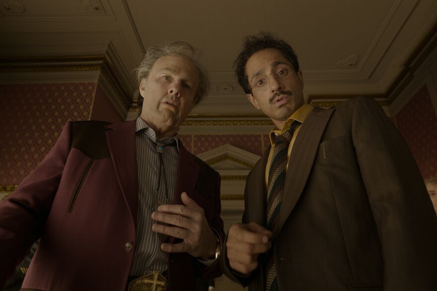 Two smartly dressed men look down towards the camera