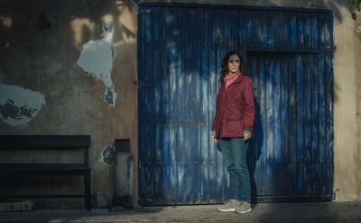 A woman stands outside a weathered blue door