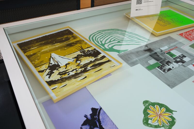 A glass fronted Display case with prints in it
