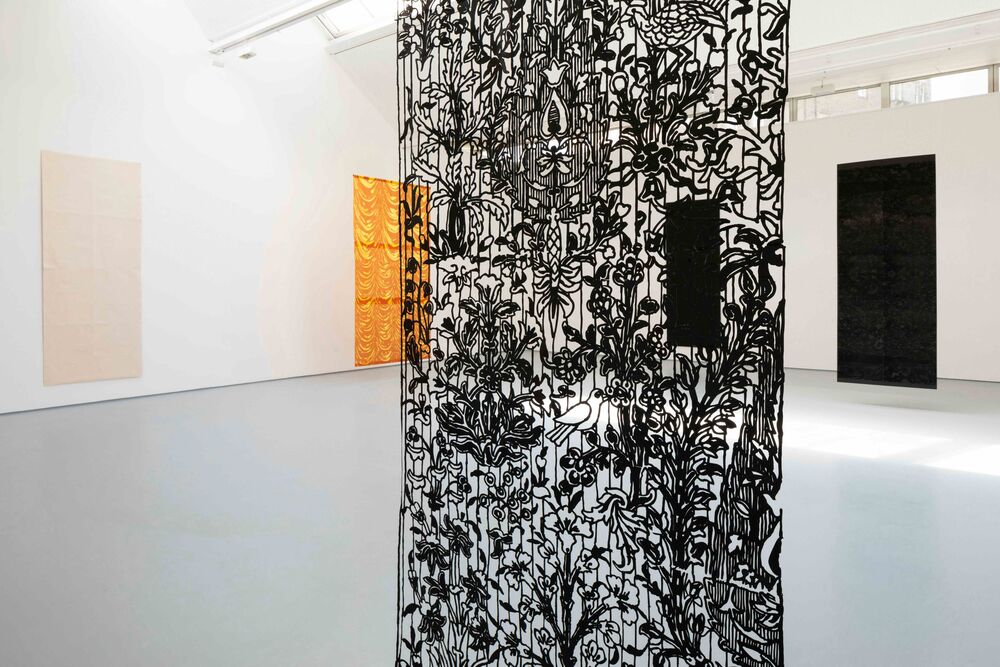 A black, hanging tapestry in DCA Galleries created by Sukaina Kubba. It has floral patterns on it created with a 3D pen.