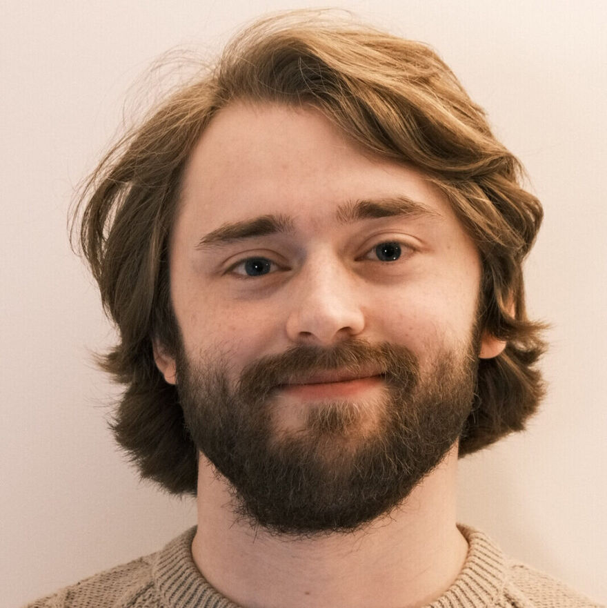 A headshot for Alec Minter, a young man with a beard
