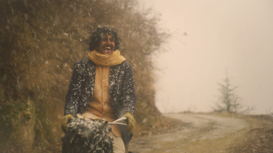 A young man laughs as he cycles through the snow in the countryside
