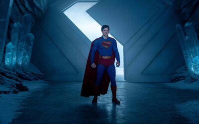 Superman stands wearing a cape and a suit.