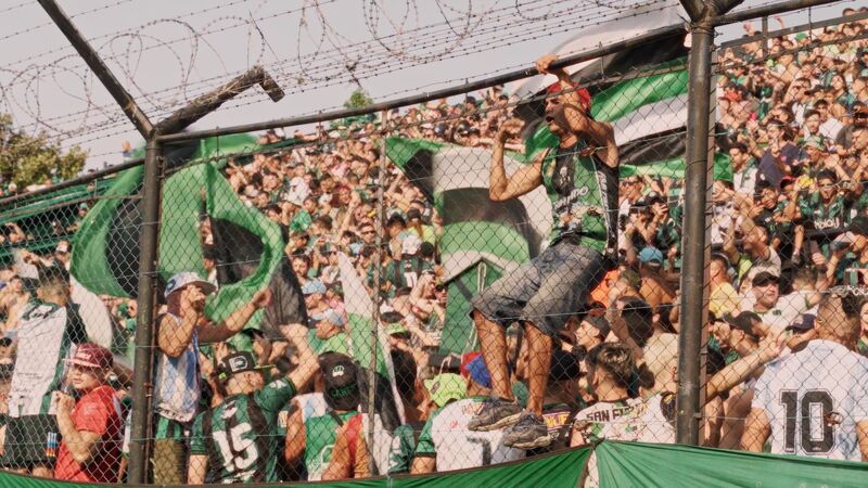 Fans climbing a fence at a football game