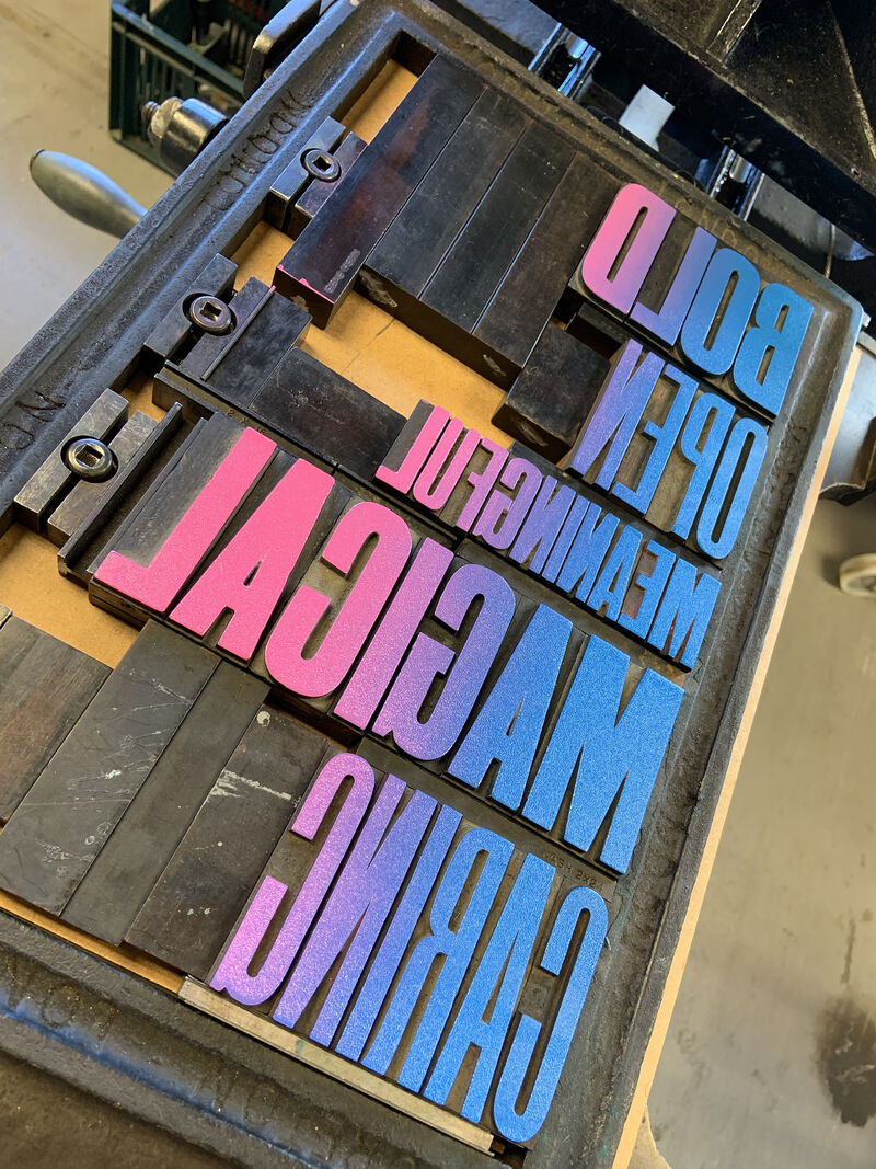 Printing press with letterpress letters with pink and blue ink