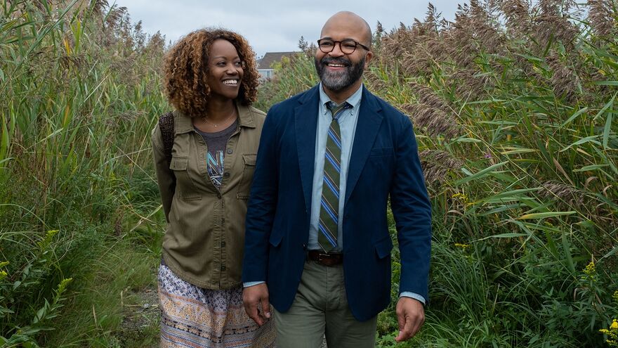 A man wearing suit and a woman walk through a field together smiling.