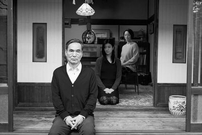 An elderly man and two women sit in a traditional Japanese house