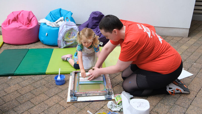 DCA artist helping a child to screen print
