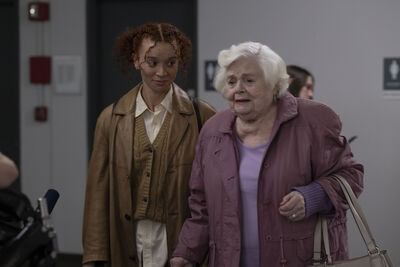 An elderly woman with white hair and a young woman walk next to one another