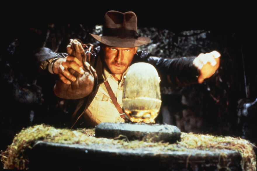 Indiana Jones reaches out carefully for a golden idol
