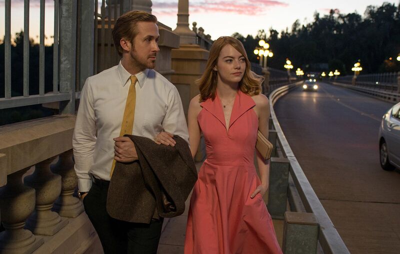 A man and a woman walk arm in arm at sunset