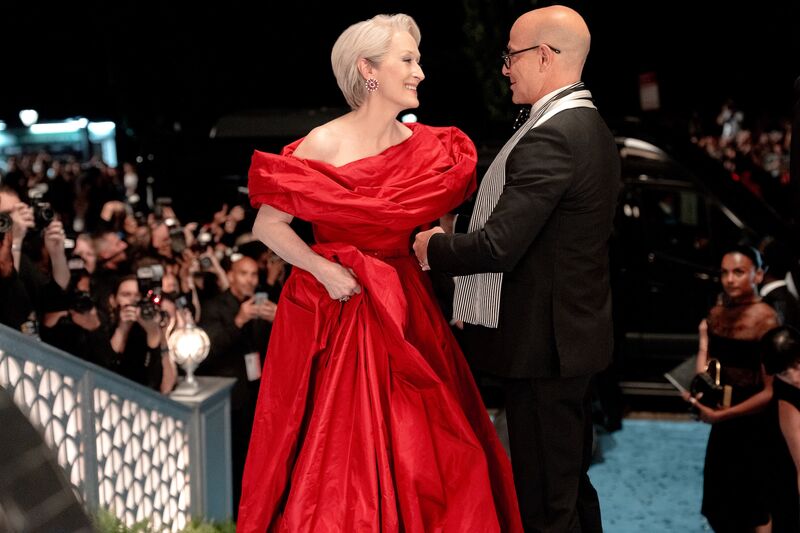 Meryl Streep and Stanley Tucci at a fashion show, she is wearing a huge red dress. 