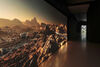 Image shows a film projection, looking along the wall at a sharp angle towards a door. The film still shows a rocky landscape, like the surface of mars. The gallery has a warm glow from the light of the projection.