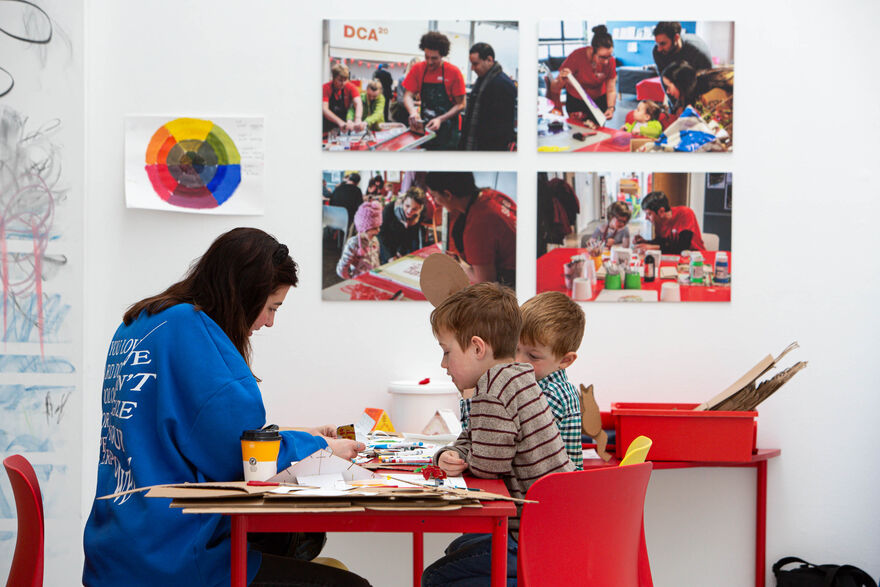 Two young boys and a member of our Learning Team work on activities together in DCA Create Space.