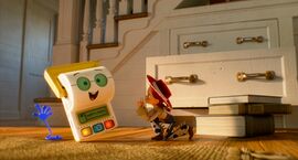 A female cowboy is on the floor shushing a toilet roll toy on the left. Behind them is a staircase and drawers with the bottom one open. Jessie is the female cowboy who features in Toy Story 2, 3, and 4.