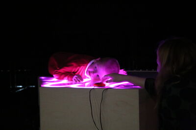 Child leaning on a box with pink lights in the top