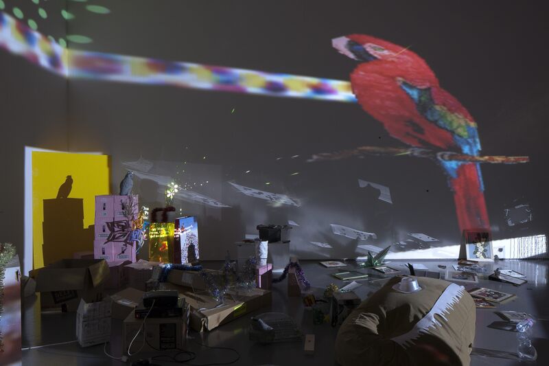 DCA Galleries during Trisha Baga's exhibition. Paintings, fake flowers and household goods are stacked, marked with luminous paint and projected upon to create a series of immersive installations.