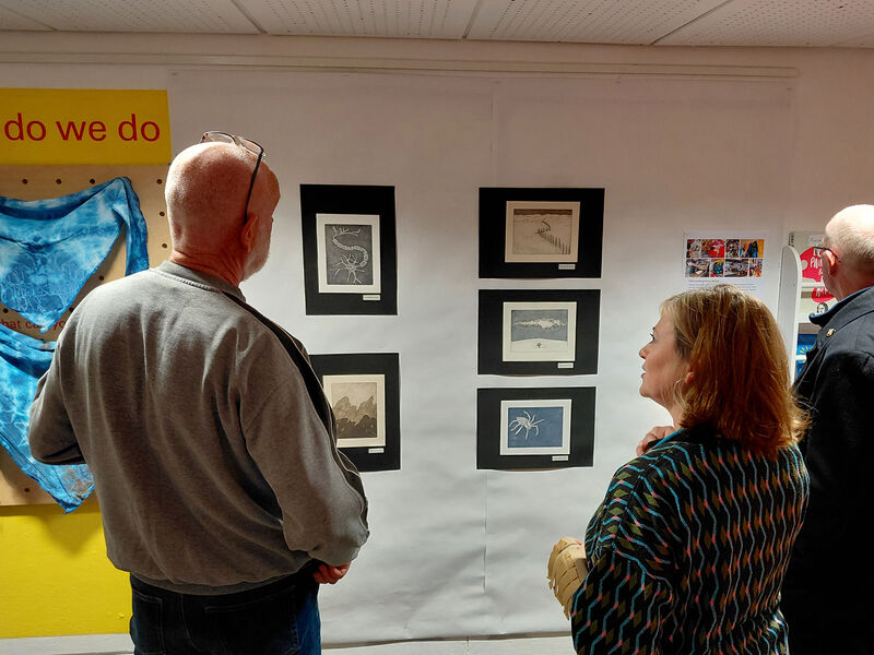 People looking at etchings on the wall of Create Space