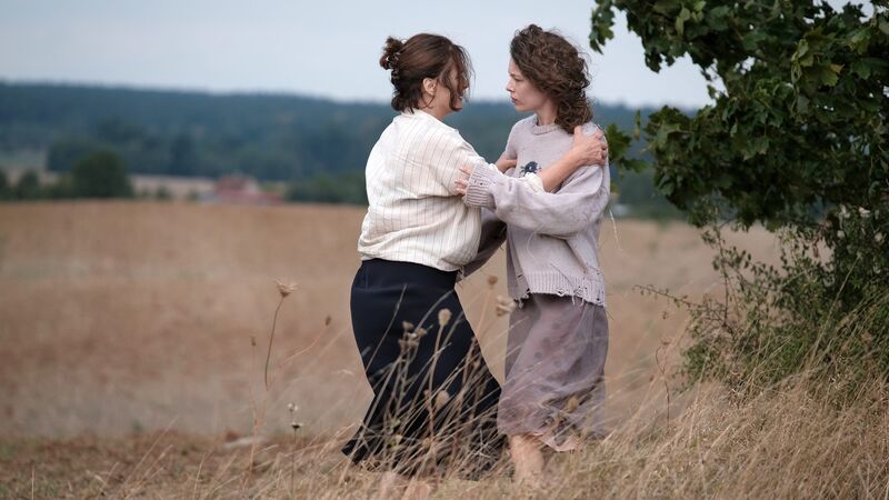 Two women hold each other in a field.