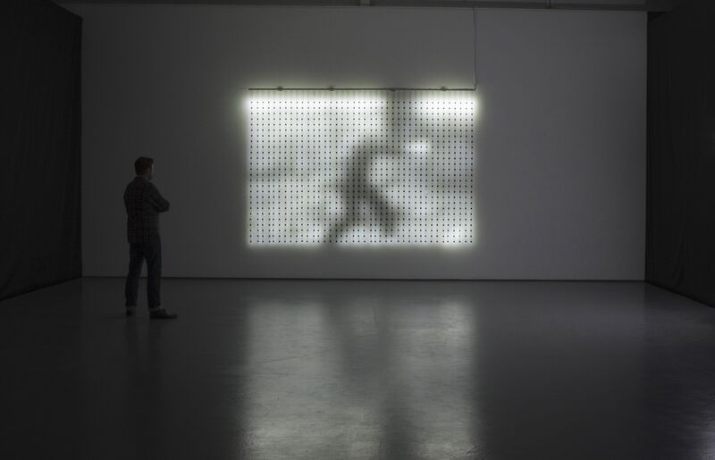 A screen made out of lights from Jim Campbell's exhibition. The shadow of a man walking can be seen on the pattern.