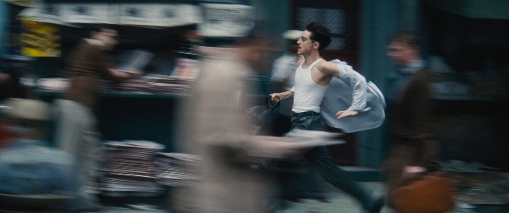 A blurry image shows a young man running down a city street