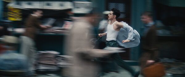 A blurry image shows a young man running down a city street