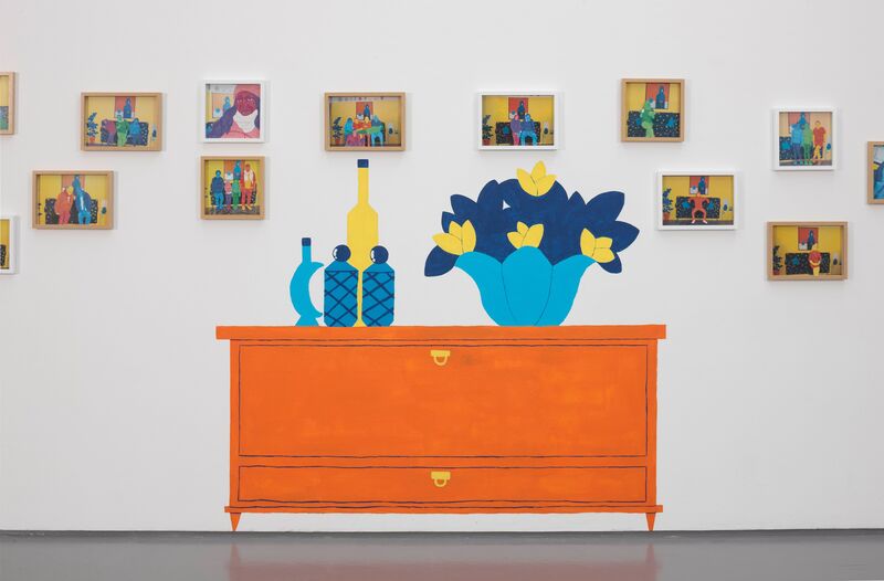 Painted directly on to the wall of DCA Galleries is a picture of  an orange chest of drawers, with blue and yellow vases and flowers on it. Surrounding this mural is small framed paintings of people, which are very colourful.
