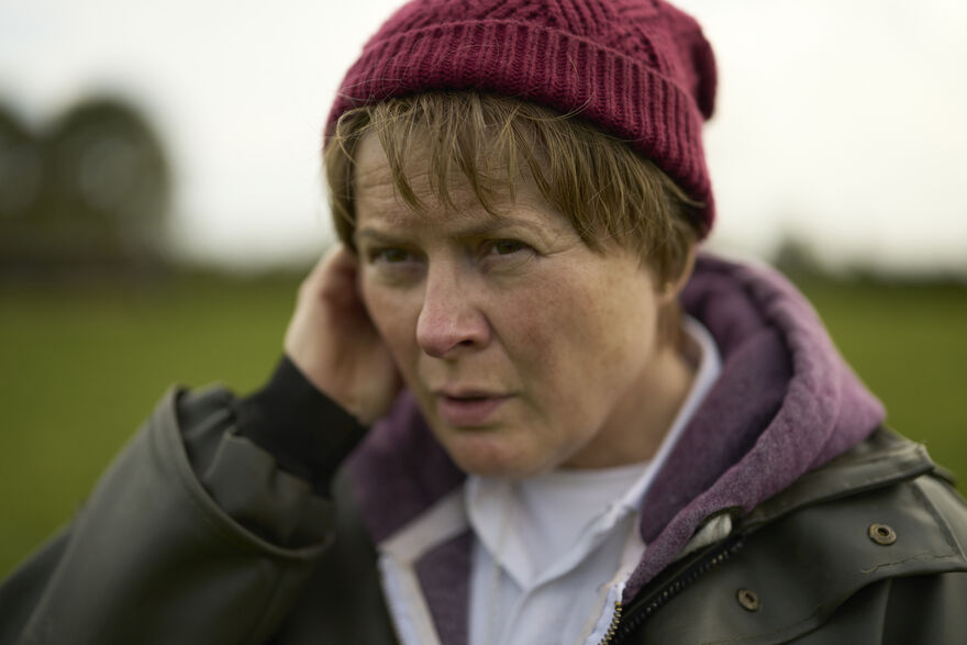 A woman in a red hat and winter coat stands outside talking on a mobile phone
