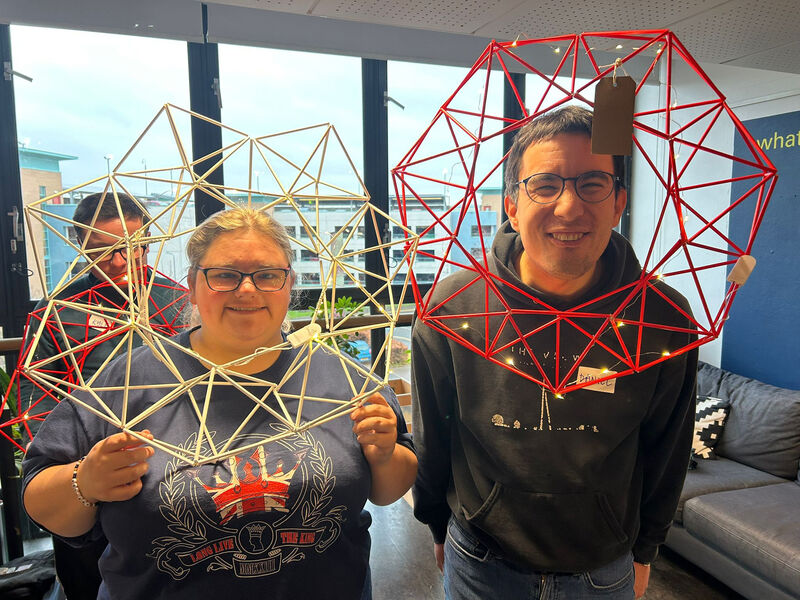 People holding up wreaths made from paper straws