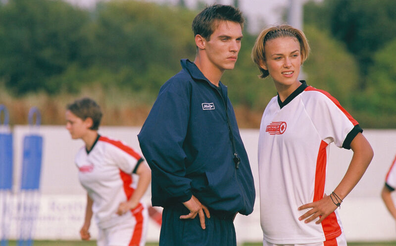 Keira Knightley and Jonathan Rhys Meyers in sports kits on a pitch