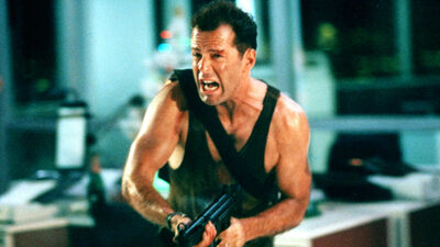 A still from Die Hard shows a man running while holding a gun.