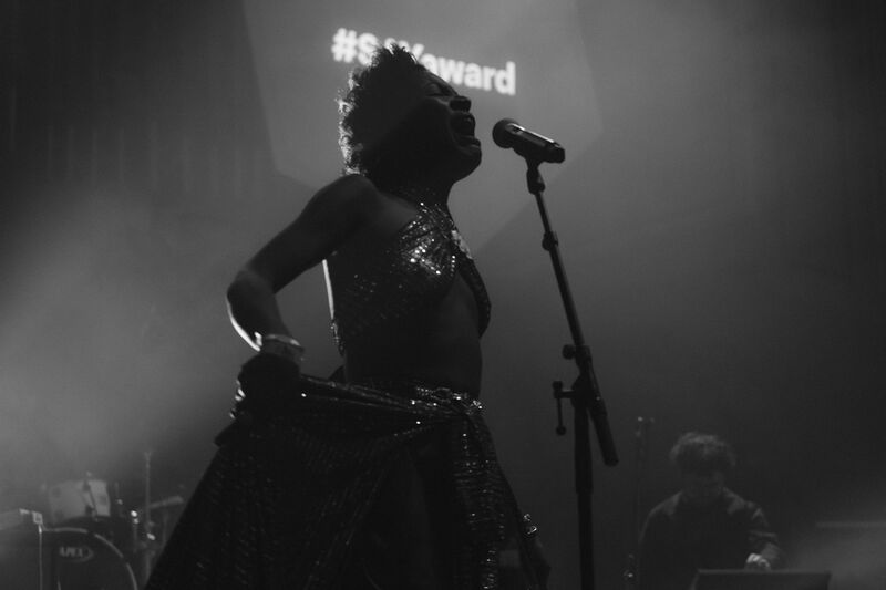 A black and white image of a woman singing on stage