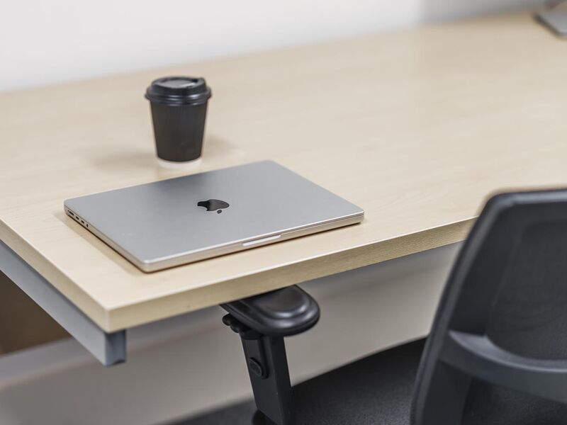 A coffee and a laptop sit on a desk