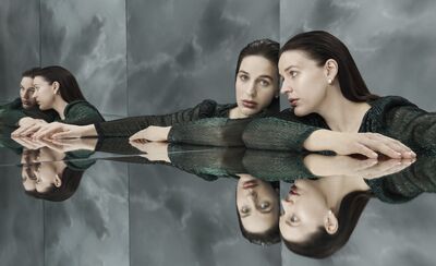 A dark haired woman is reflected many times in mirrors