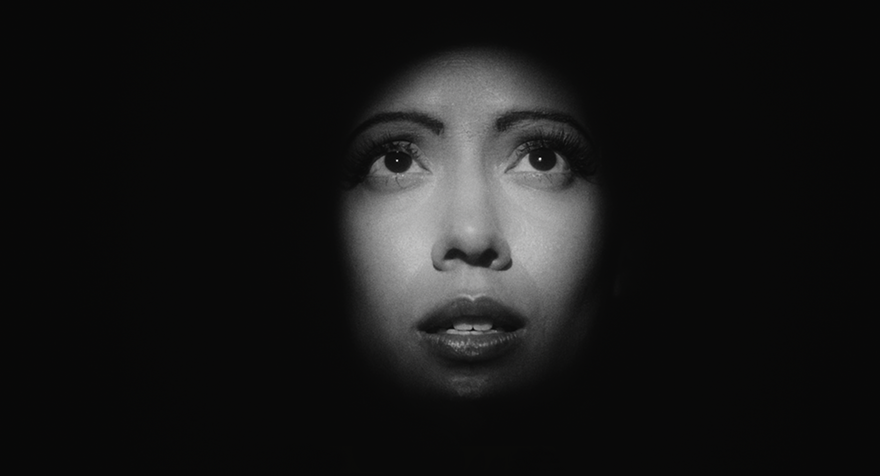 A woman's face peers through the darkness, concerned.