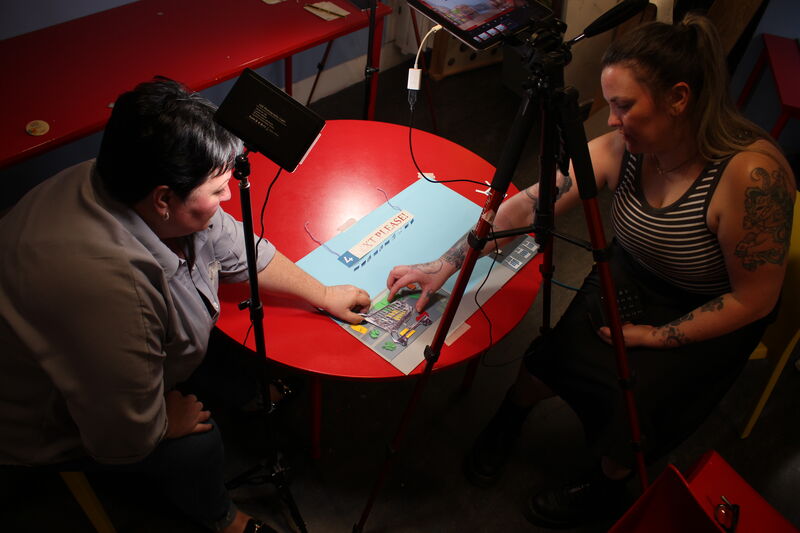 Two people animating a drawing of a shopping trolly