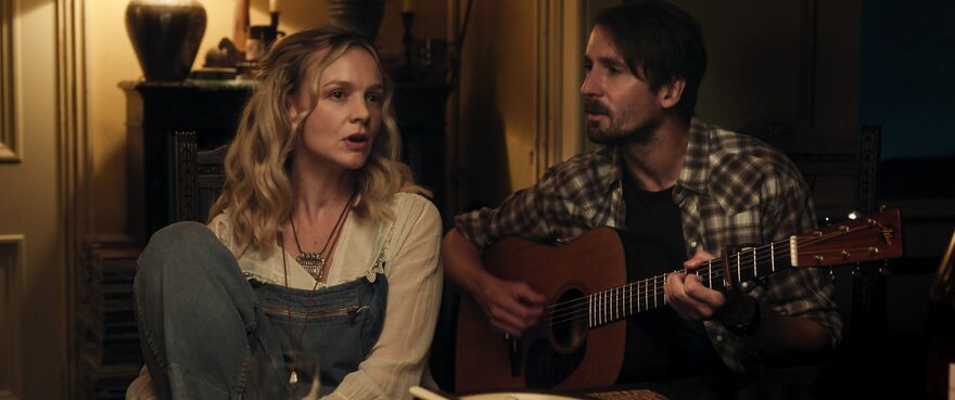 A blonde woman sings while a man plays guitar.
