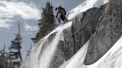 A skier jumps from a rocky crag.